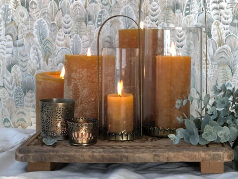 Cluster of lit pillar candles on a wooden tray