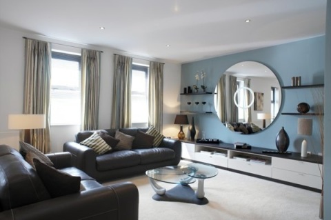 Living room styled with a large round mirror above a media console