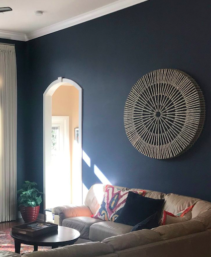 Dark navy living room wall showing how daylight through an archway changes the paint’s apparent tone