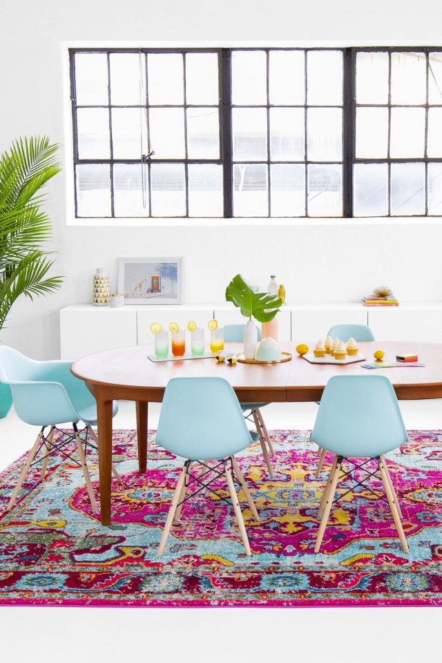 Dining table with pastel chairs set on a colourful patterned rug