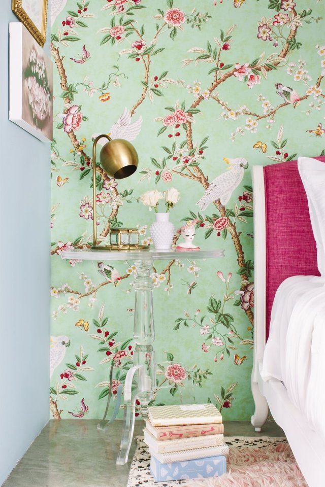 Bedside nook with green floral wallpaper beside a pink upholstered bed