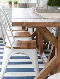Wooden dining table and white chairs on a blue and white striped rug