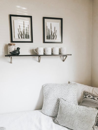 Neutral shelf styled with framed botanical prints and soft cushions