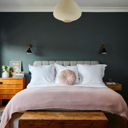 Bedroom with a dark teal wall and blush pink bedding