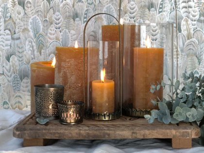 Lit pillar candles with eucalyptus sprigs on a wooden tray